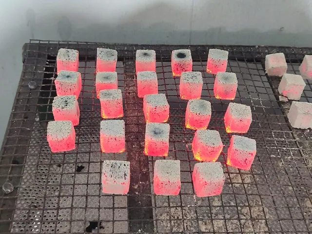 Rack of glowing coconut charcoal briquettes during quality testing in Boyolali